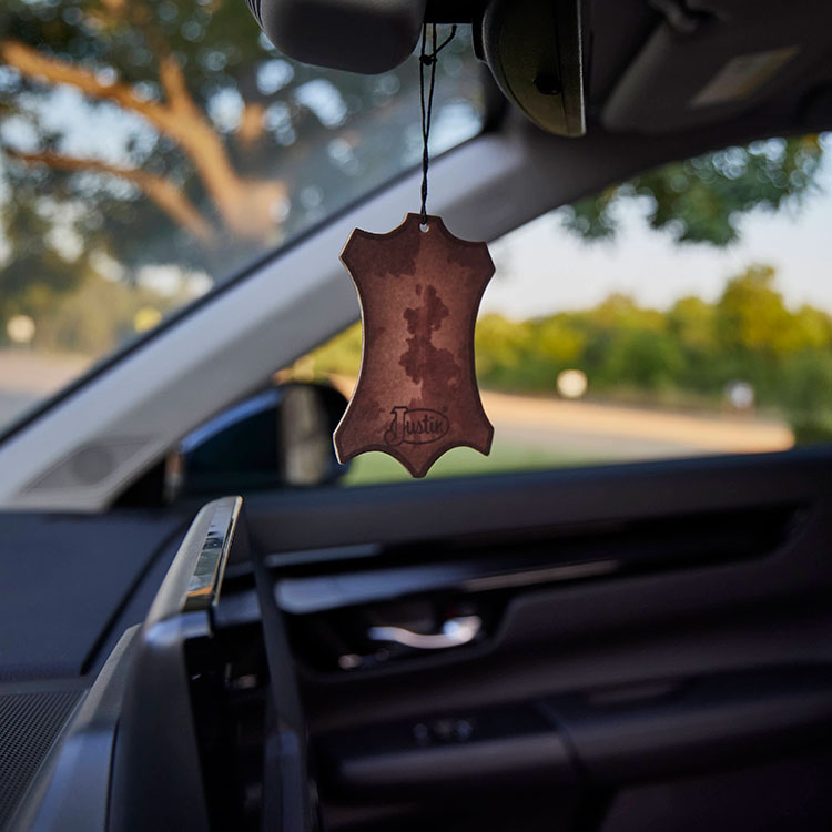 A Justin Air Freshener hanging from a car mirror.